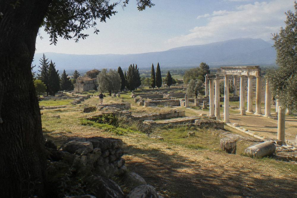 A wide view over ancient foundations towards distant hazy mountains