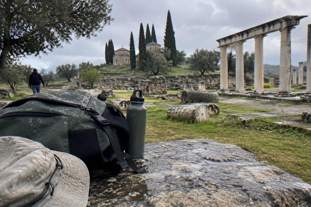 A day pack, water bottle and hat resting on a stone at an ancient site