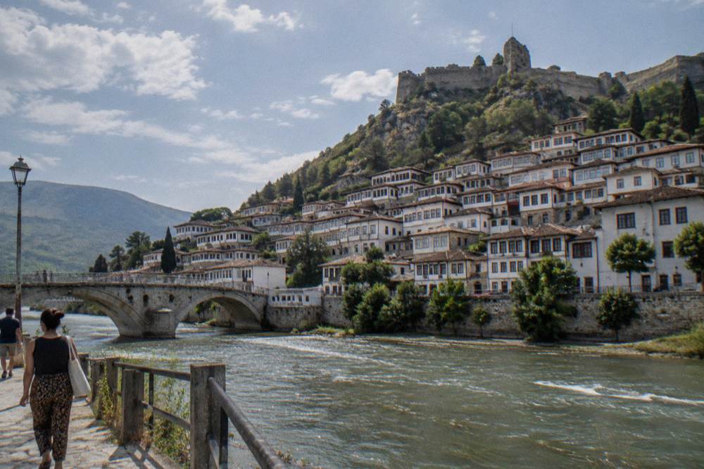 Rows of white houses with many windows above the green Osum river in Berat