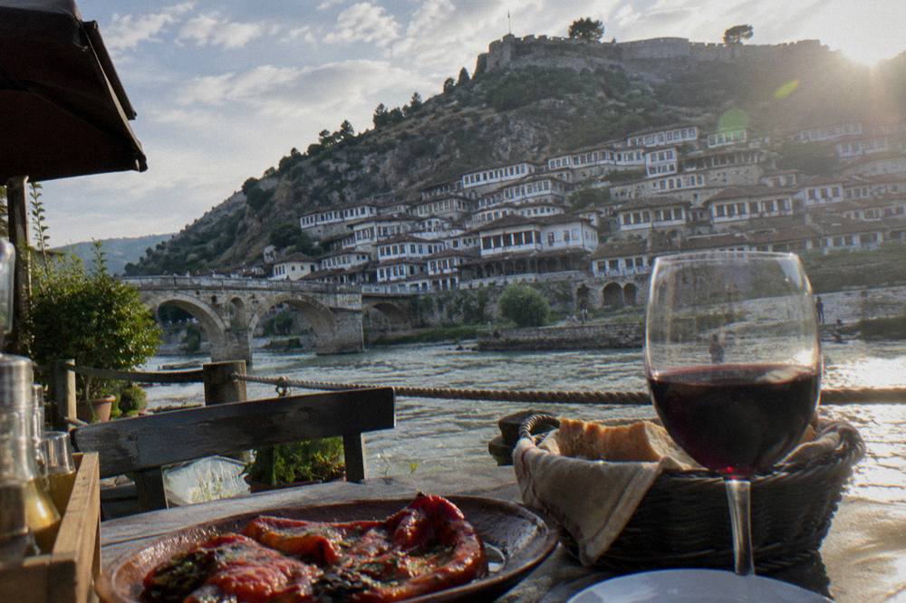 A table with baked peppers, bread and a glass of red wine on a restaurant terrace