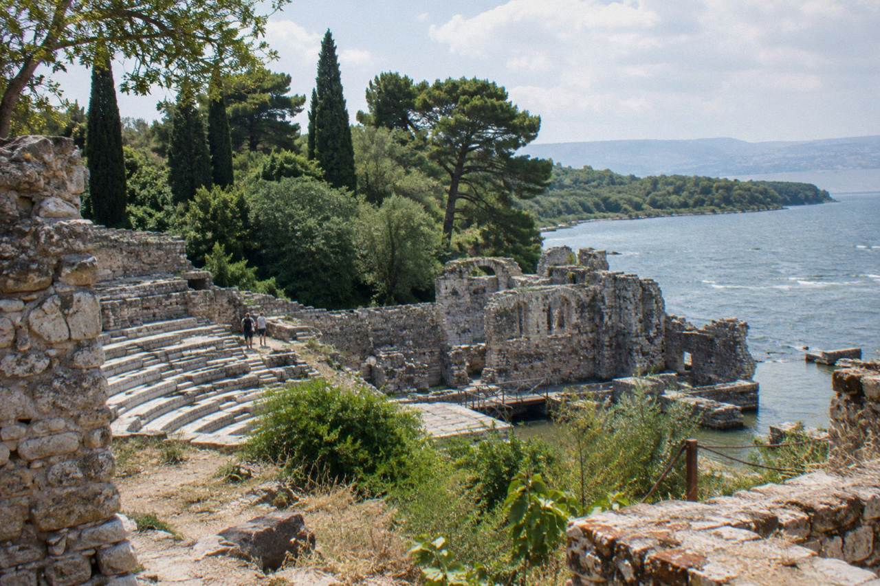 Ancient stone walls of Butrint rising above green woodland near a channel of water