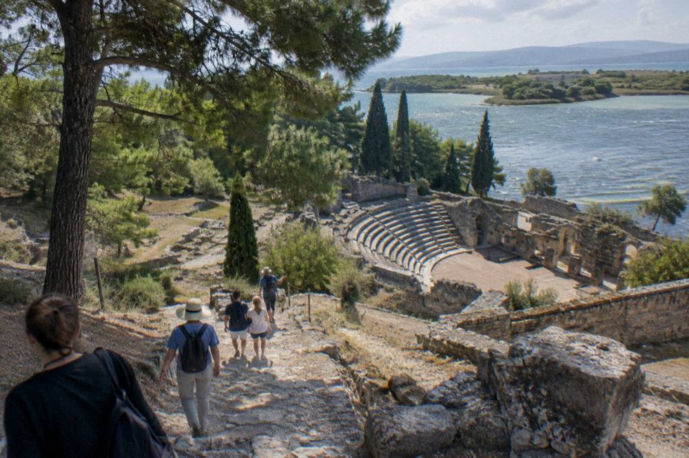A guide leading a small group of visitors along a stone path among ruins