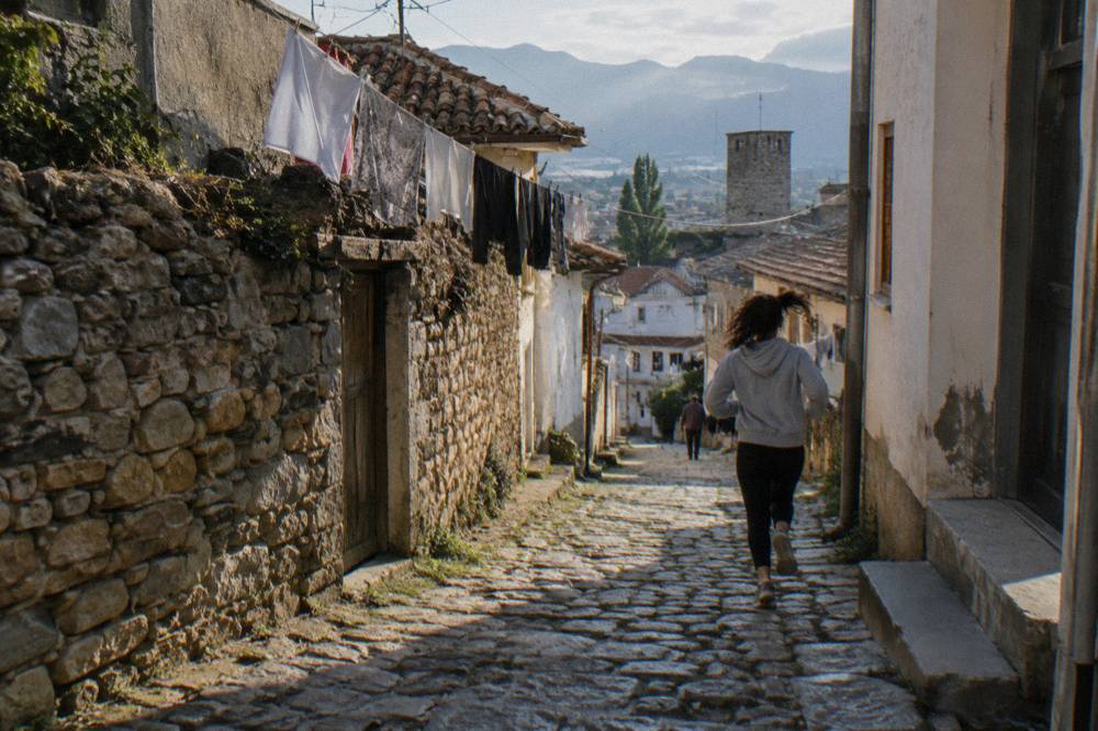 A narrow cobbled lane in Elbasan old town with old houses and laundry overhead