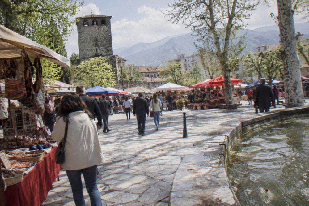 Colourful festival stalls and crowds in an old town square in spring sunshine