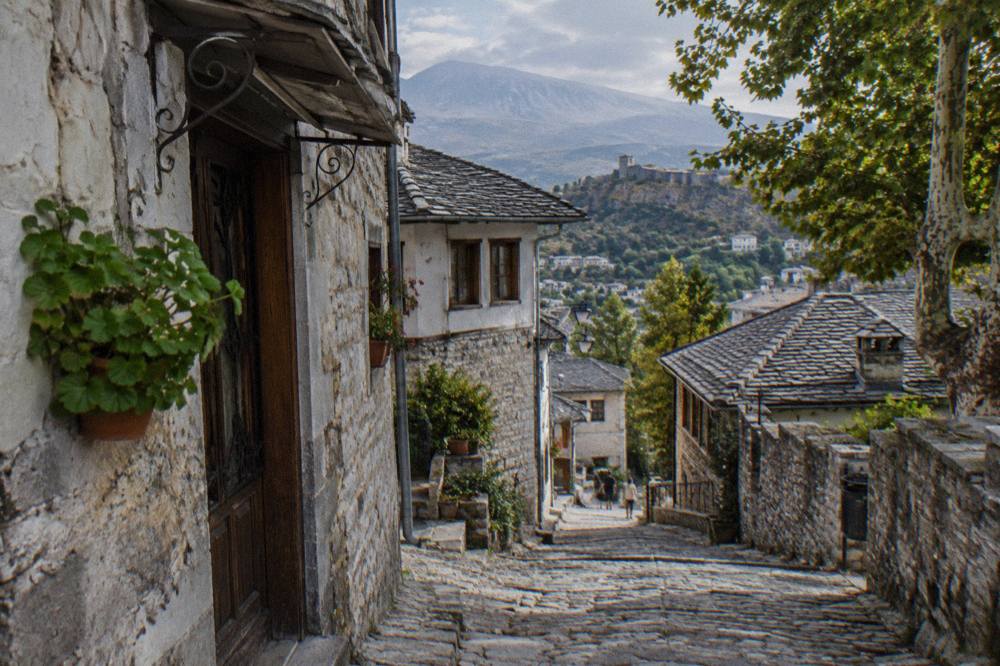 A cobbled stone lane winding between grey-walled Ottoman houses in Gjirokaster old town