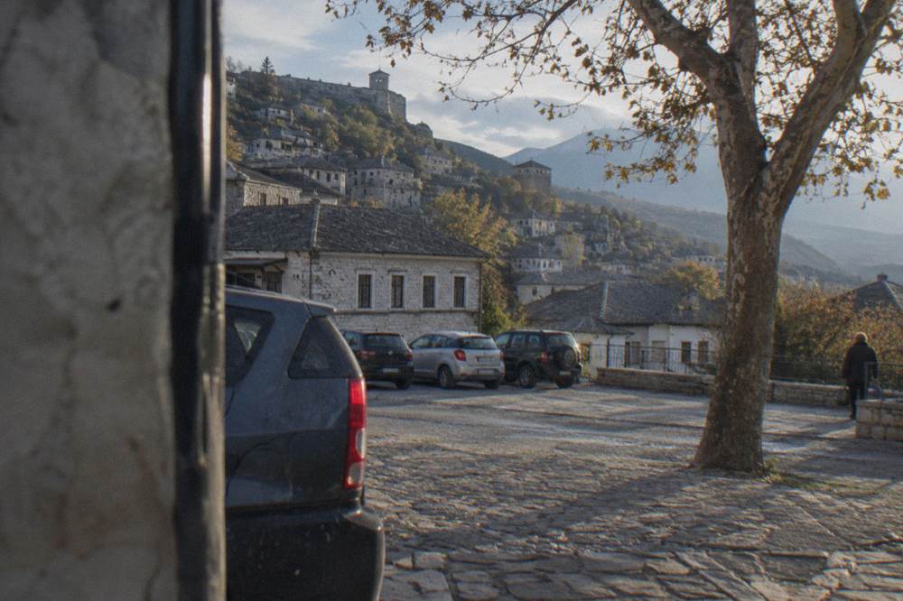 A car park and stone houses at the edge of Gjirokaster old town in late afternoon light