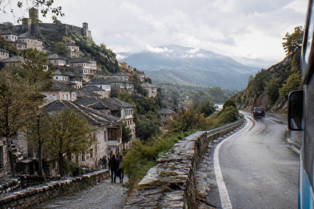 A mountain road winding through green hills on the route from Gjirokaster towards the southern coast