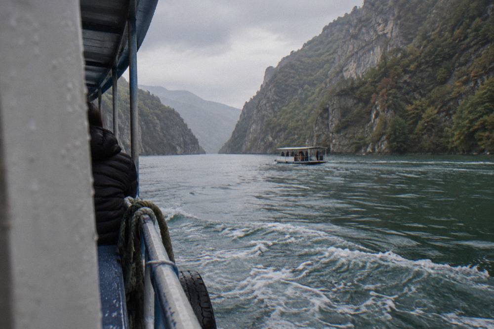 Steep forested canyon walls rising above calm green water on Komani Lake