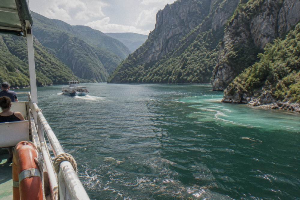Turquoise shallow water where the Shala River meets Komani Lake between rocky slopes