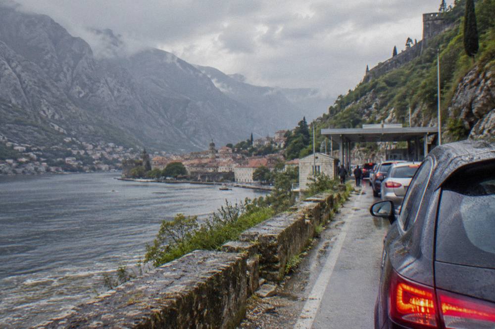Queue of cars waiting at a small road border checkpoint between hills