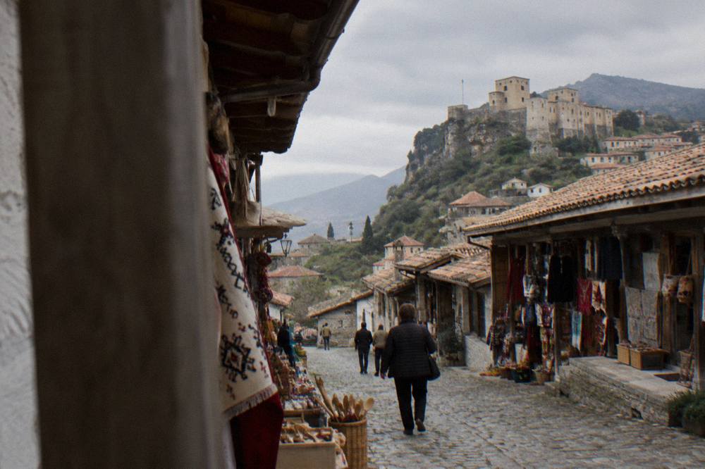 A narrow cobbled bazaar street in Kruja lined with small shops under wooden eaves