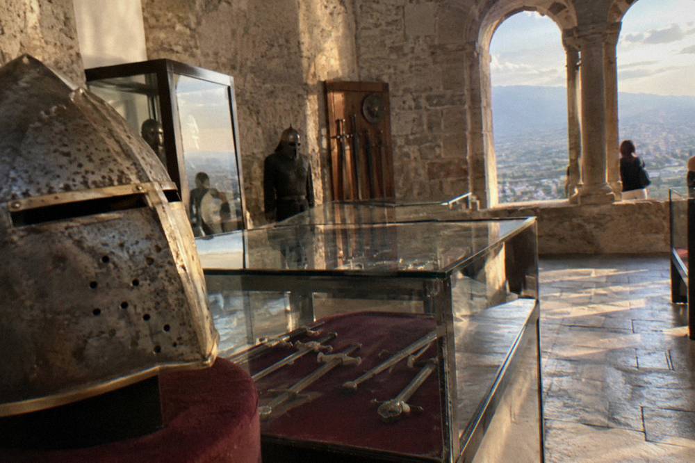 A museum hall with medieval helmets, swords and display cases inside Kruja Castle