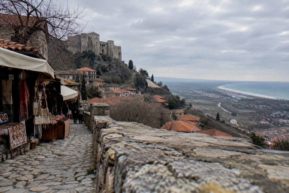 A view from a castle wall over rooftops to a wide coastal plain in the distance