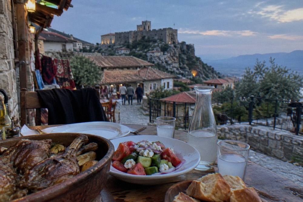 A table with baked lamb dishes, salad and small glasses of raki in a small restaurant