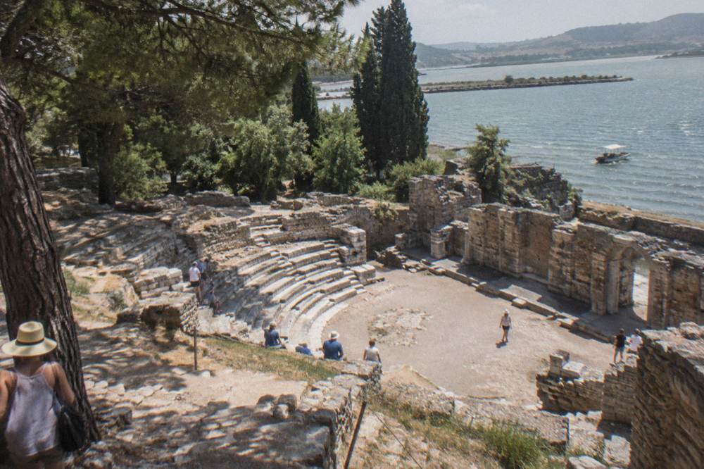 Ancient stone theatre ruins surrounded by trees at the Butrint archaeological site