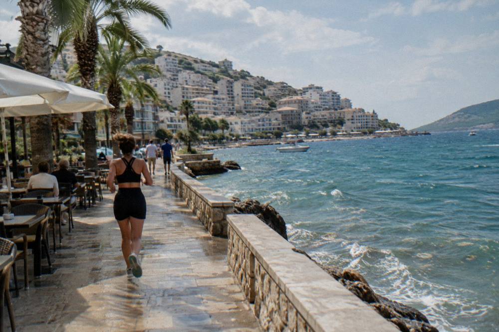 A seaside promenade with palm trees and cafe tables in Saranda on a bright afternoon