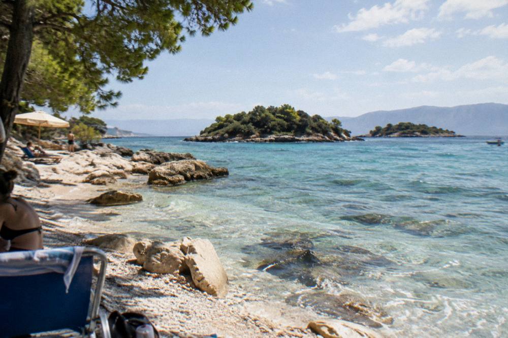 White sand, smooth rocks and transparent shallow water at a quiet cove near Ksamil in the evening