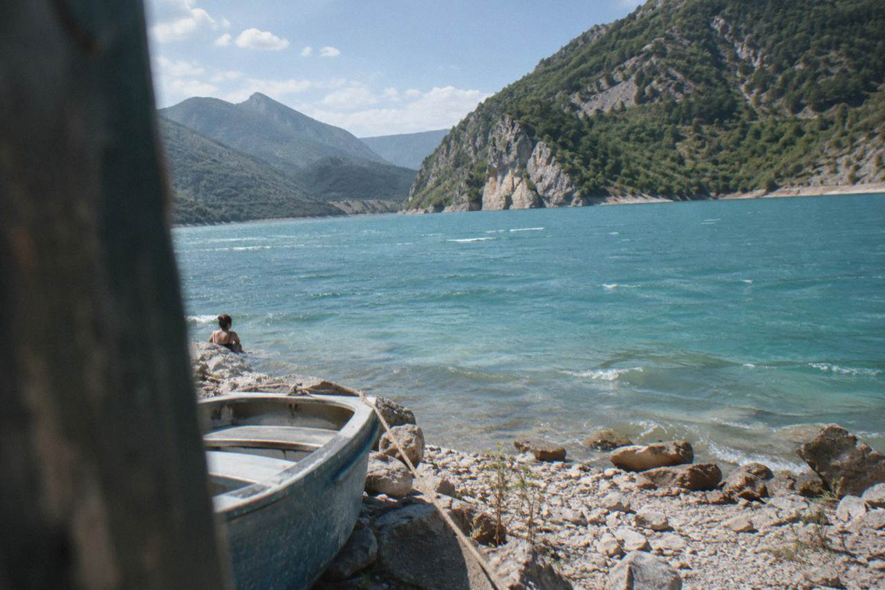 A turquoise mountain reservoir framed by steep rocky slopes under a clear sky