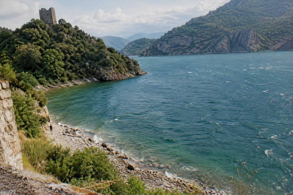 A stone castle keep on a green hill overlooking a river valley