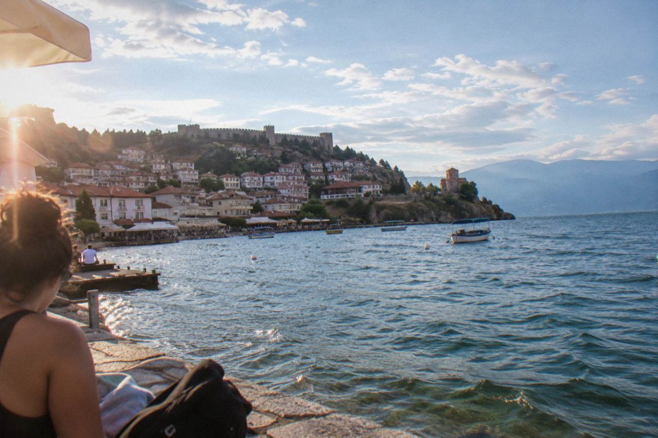 A lakeside town with a hilltop fortress above a large blue mountain lake