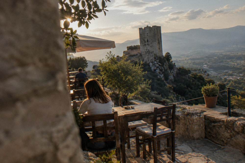 A terrace inside castle walls with tables, overlooking a green valley