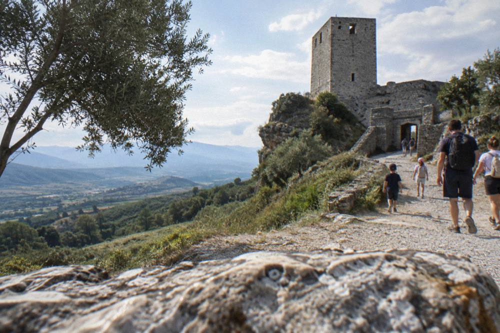 A family walking a gravel path toward a castle entrance on a sunny morning