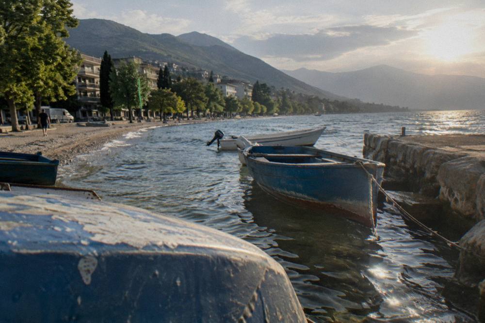 Fishing boats moored in clear shallow water beside a stone jetty