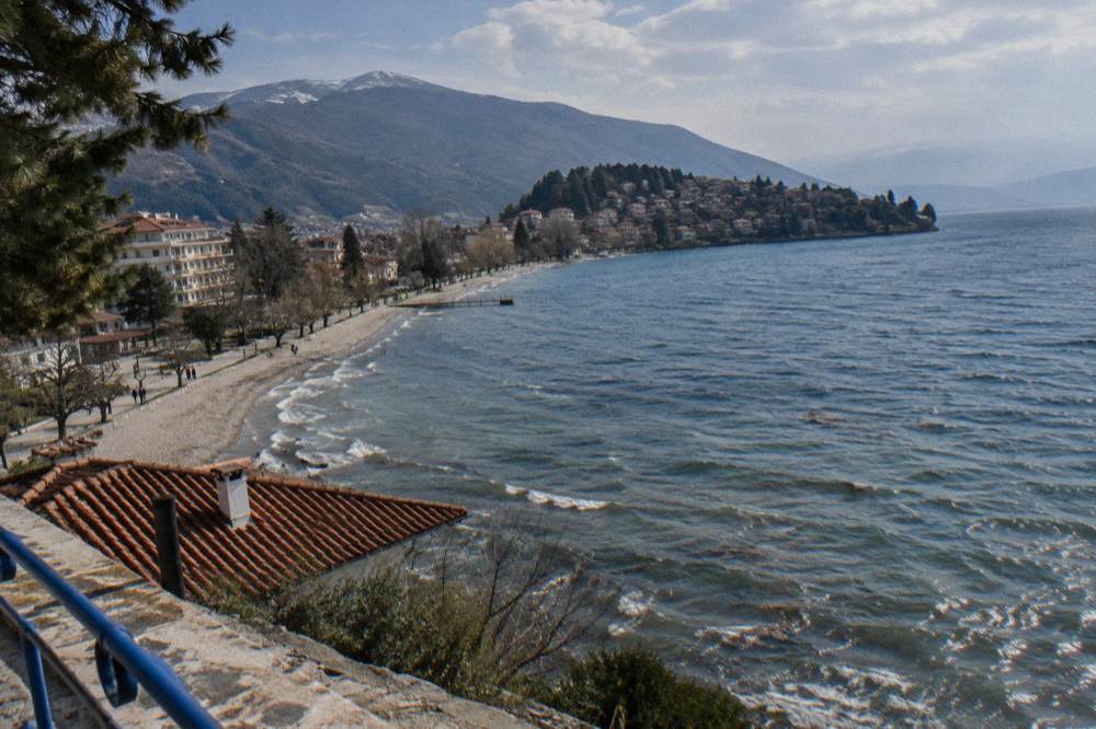 A small village of tiled roofs on a green peninsula reaching into a wide lake