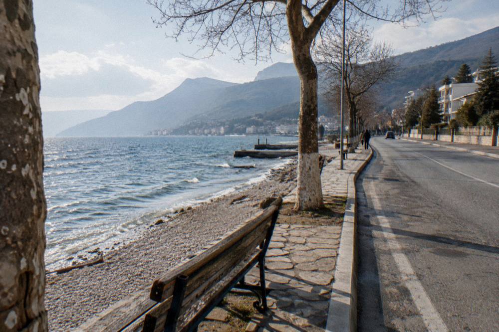 A quiet shoreline road curving away along the edge of a large blue lake