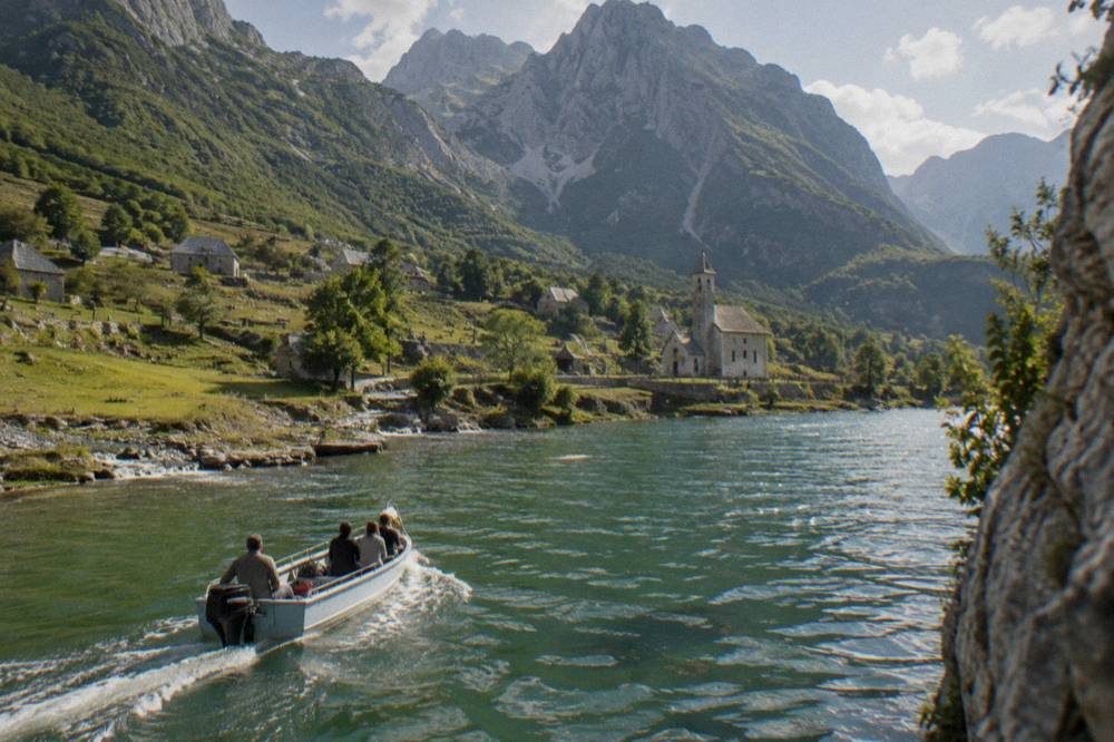 A boat crossing a narrow green lake between steep rocky slopes
