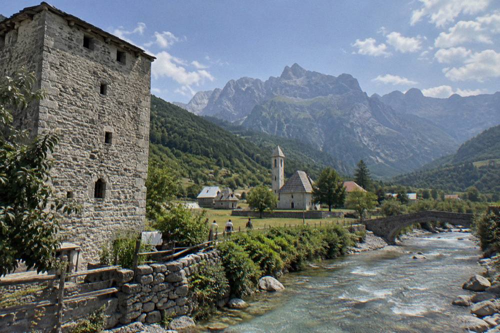 A traditional stone tower house with thick walls and small windows in a mountain village