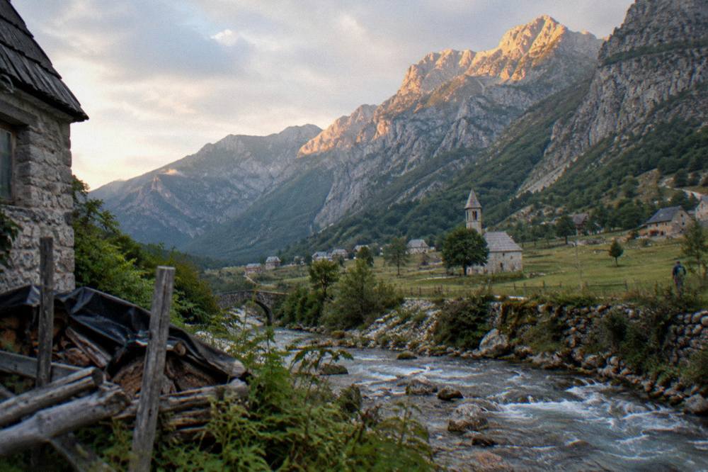 A wide view of a mountain valley at golden hour with peaks catching the last light