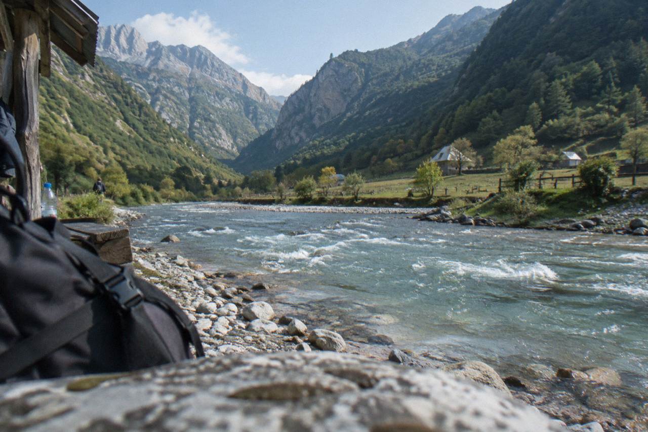 Green mountain valley with a river running between steep forested slopes under a clear sky