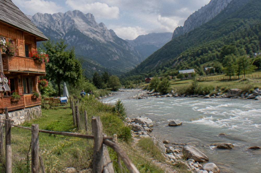 Wooden guesthouse with flower boxes standing in an alpine meadow below peaks