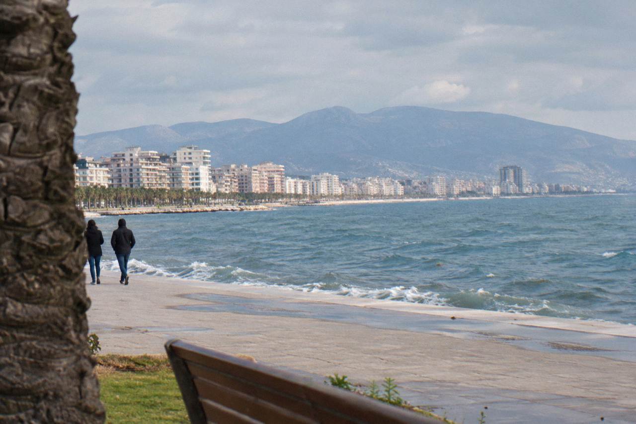 A coastal city skyline seen across a wide bay with mountains rising behind the water
