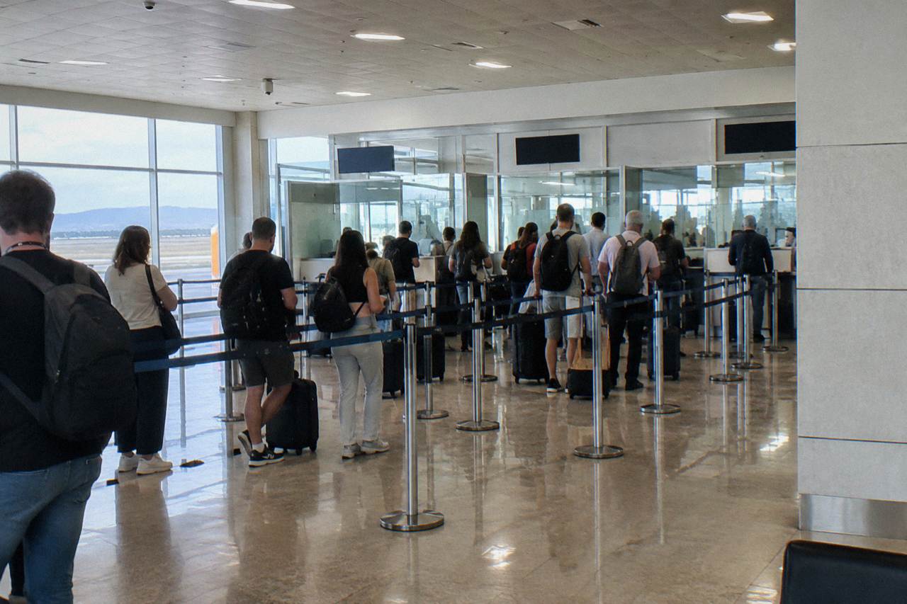 Passport control desks at an airport arrivals hall with travellers queuing