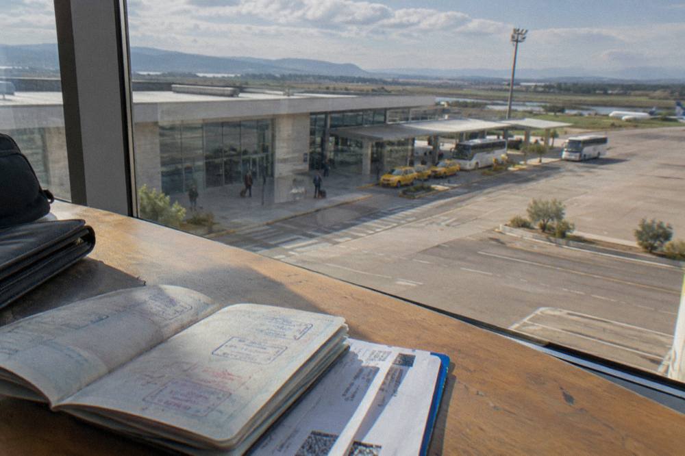 A passport open on a desk beside boarding passes and a travel wallet
