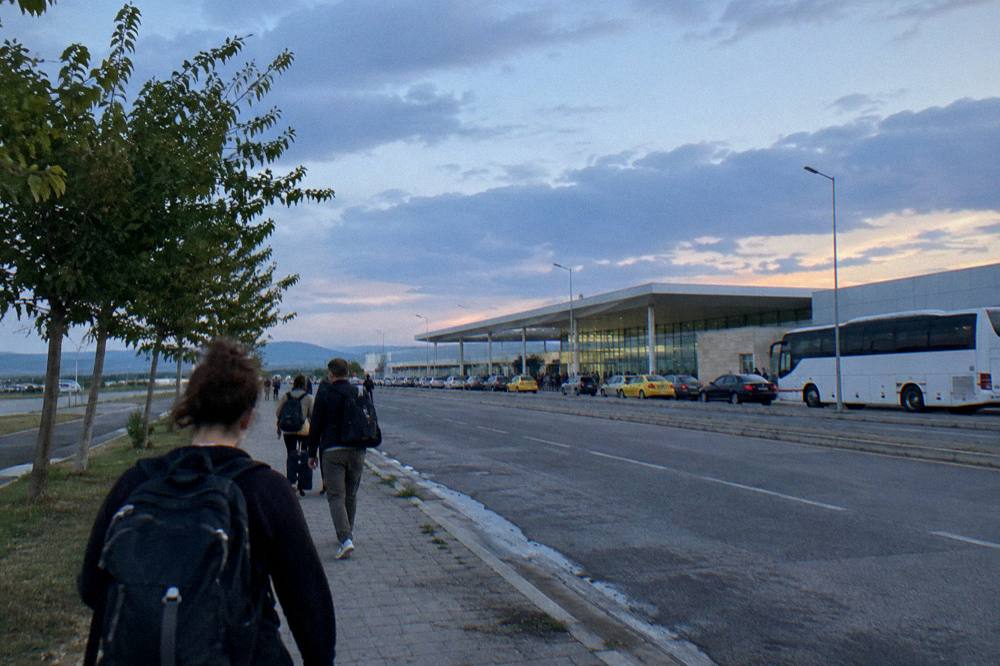 Travellers walking with backpacks along a tree-lined city street