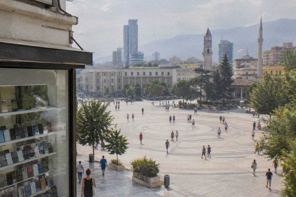 A small mobile phone shop front with handsets displayed in the window on a Tirana street