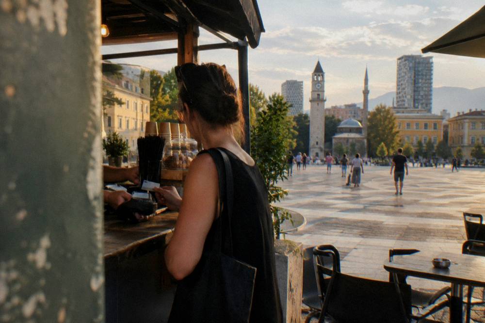 A customer paying with a bank card at a small cafe counter in Tirana