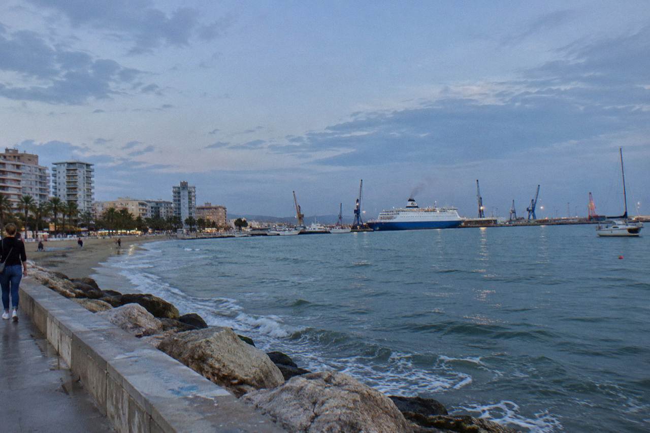 A ferry berthed at the Adriatic port of Durres with cranes and moored boats along the quay