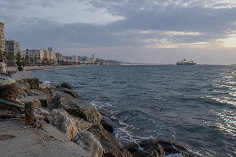 An overnight ferry at sea with a darkening sky and the lights of a distant coastline