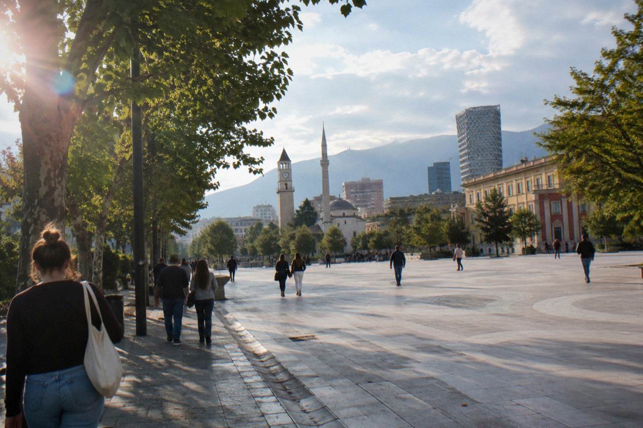 People walking and chatting on a leafy pedestrian street in central Tirana