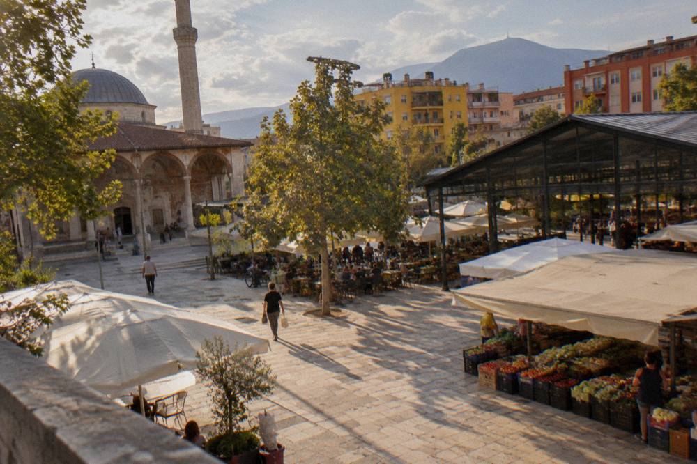 An old mosque with a frescoed portico beside a modern city square