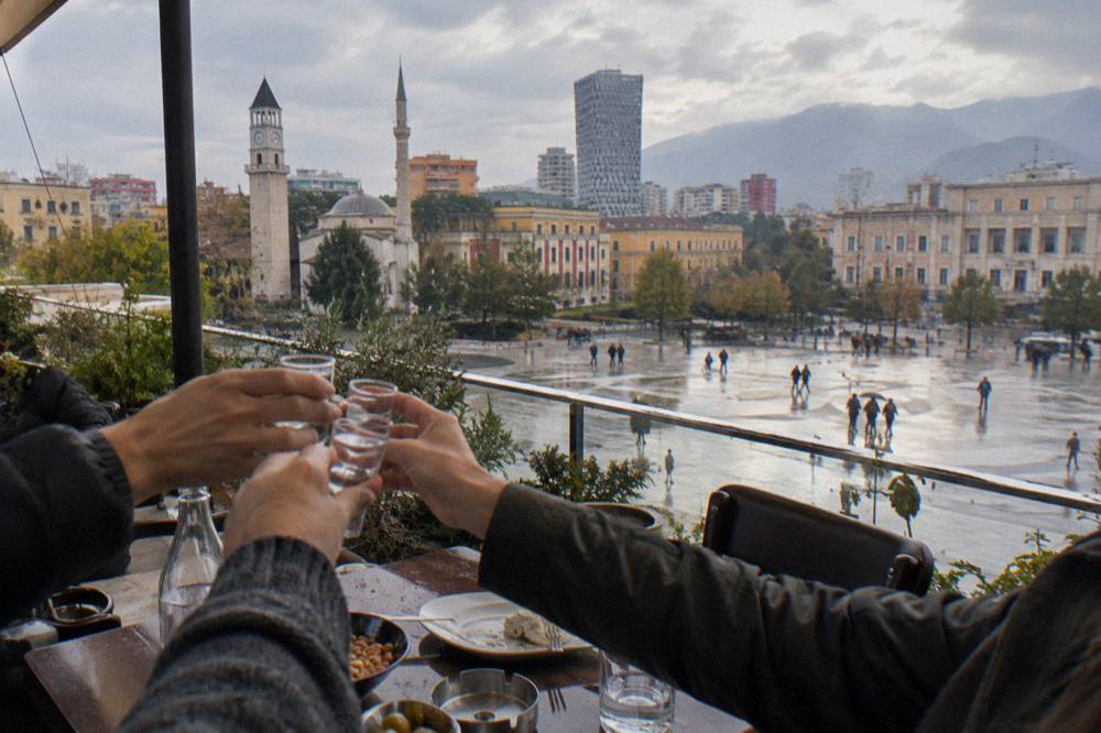 Friends raising small glasses of raki in a toast at a restaurant in Tirana