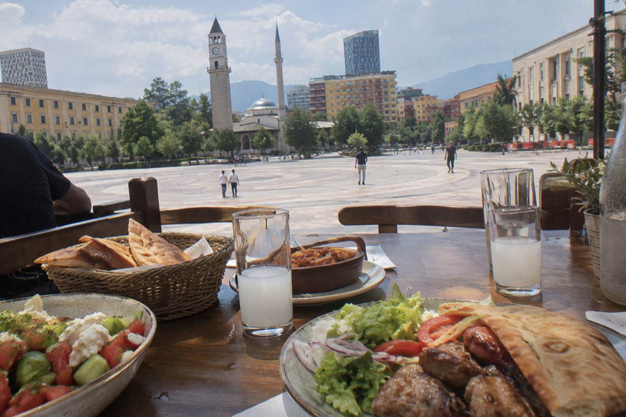 A table of Albanian dishes with bread, salad and glasses of raki in a Tirana restaurant