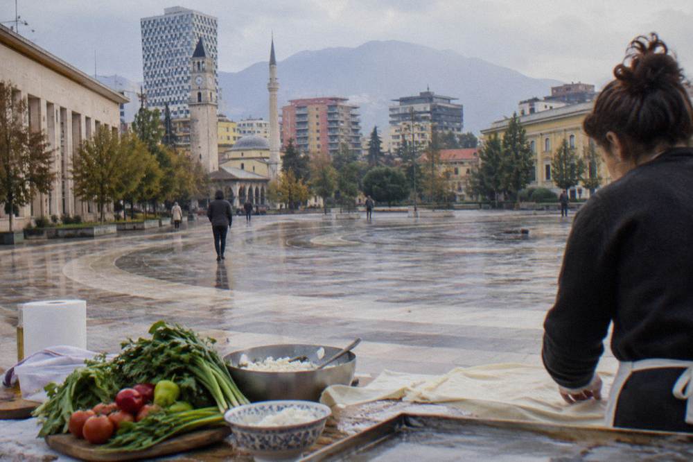 A cooking class table with fresh vegetables, filo pastry and bowls of cheese in Tirana