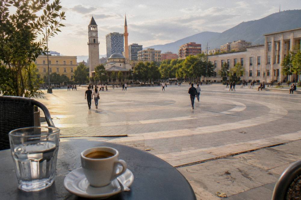 An espresso cup and a glass of water on a small cafe table in Tirana