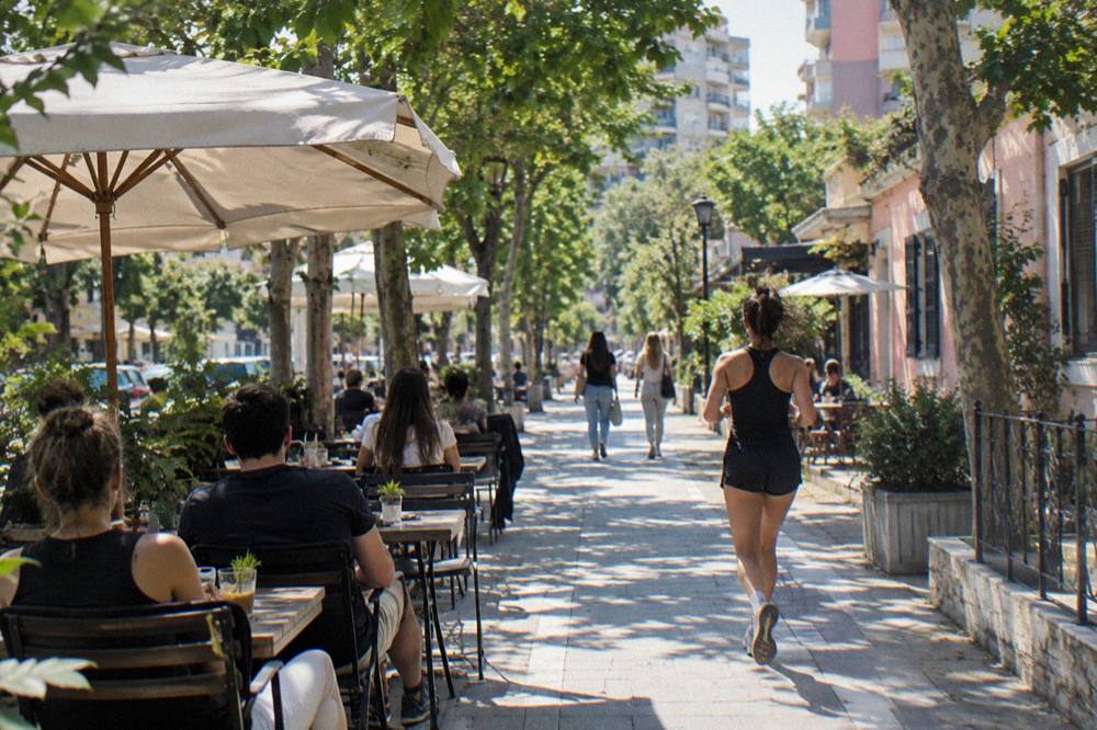 Diners at pavement tables along a leafy street in the Blloku quarter of Tirana