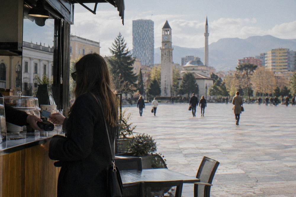 Customer paying with a contactless bank card at a restaurant counter in Tirana